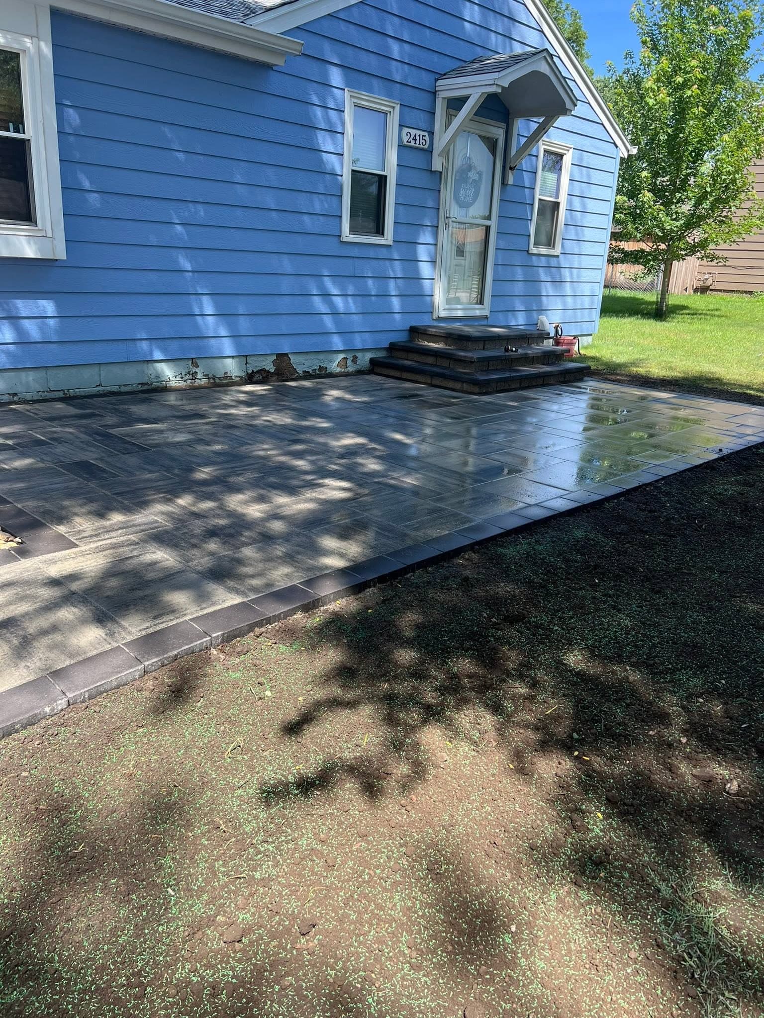 Dark paver patio and steps at a blue house front entry