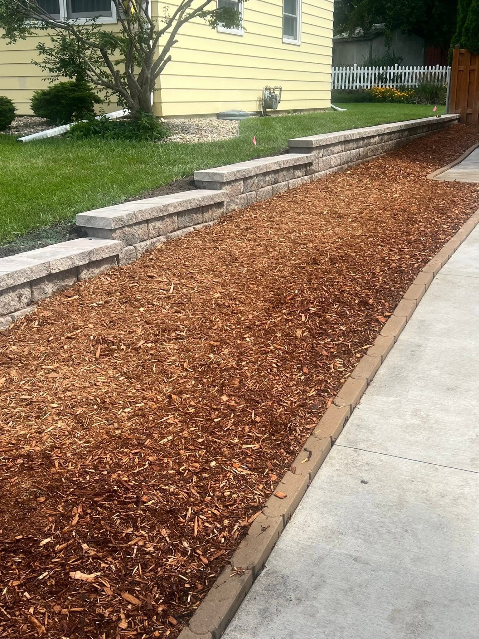 Mulch bed between a sidewalk and block wall
