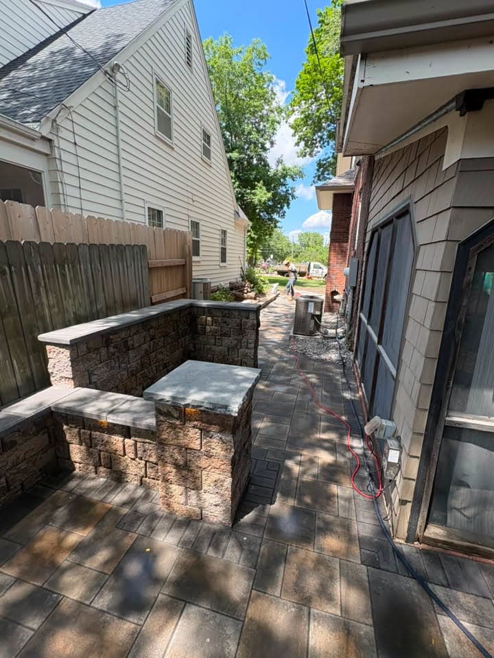 Stone-wrapped island and seat wall on a dark paver side patio