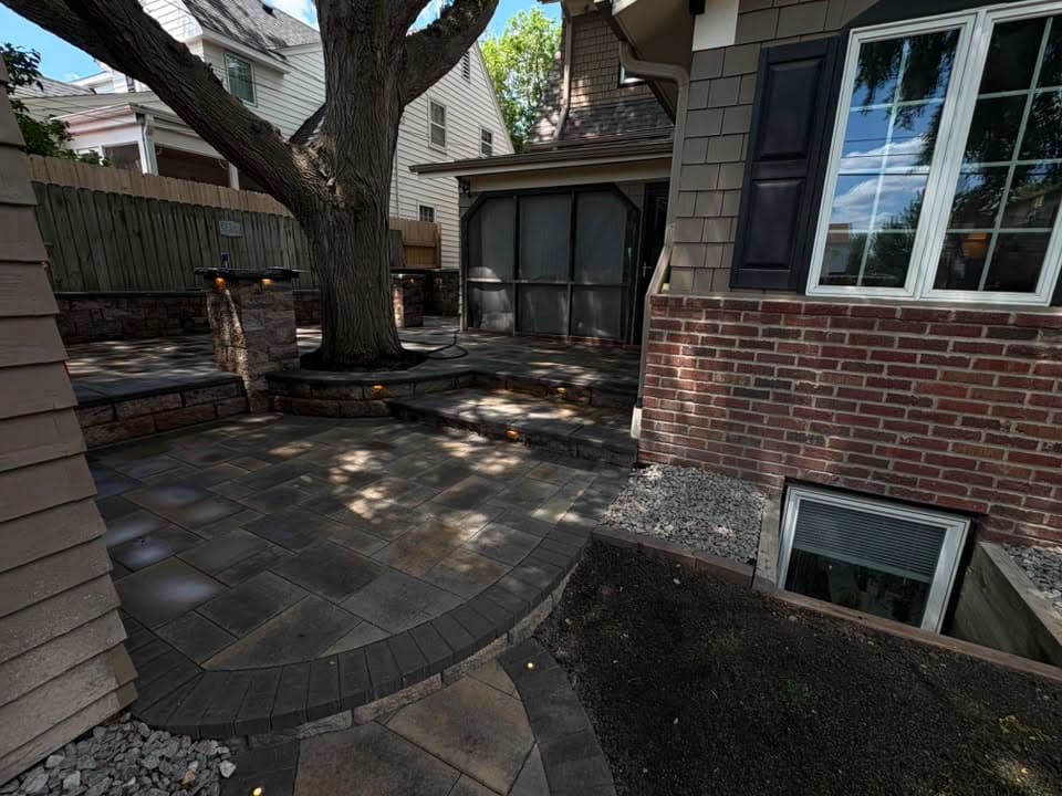 Dark paver patio with a seat wall around a tree