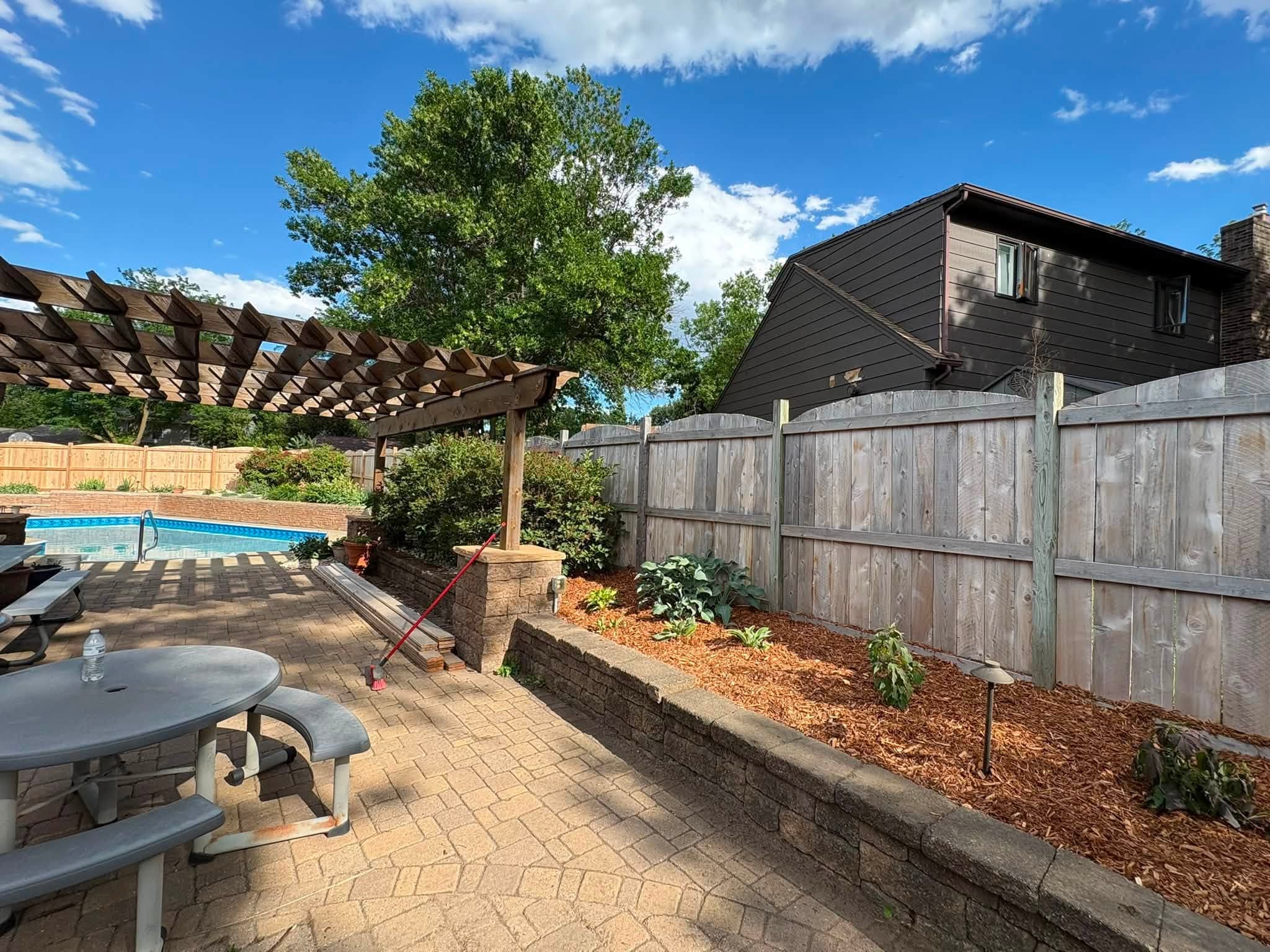 Pergola and planter wall on a paver patio beside a pool