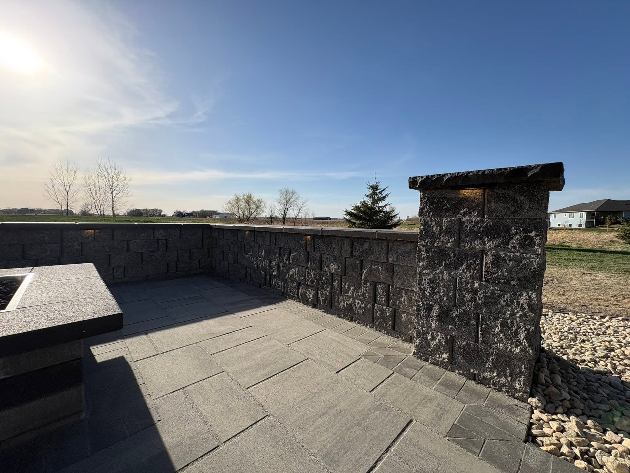 Seat wall and stone pillar bordering a paver patio