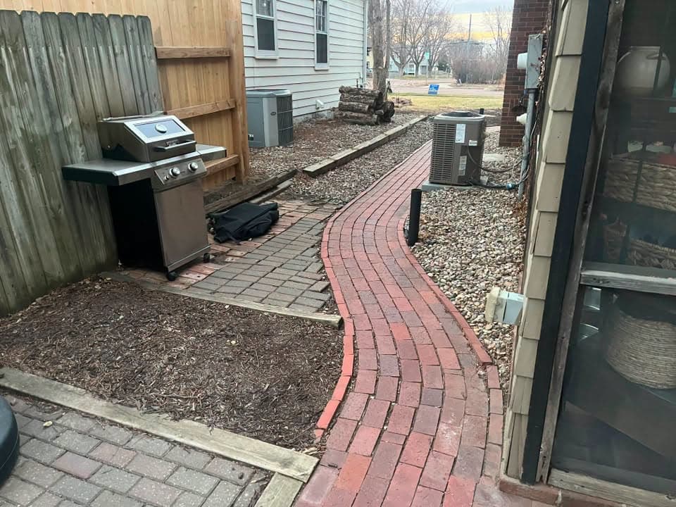 Red brick paver walkway beside a grill