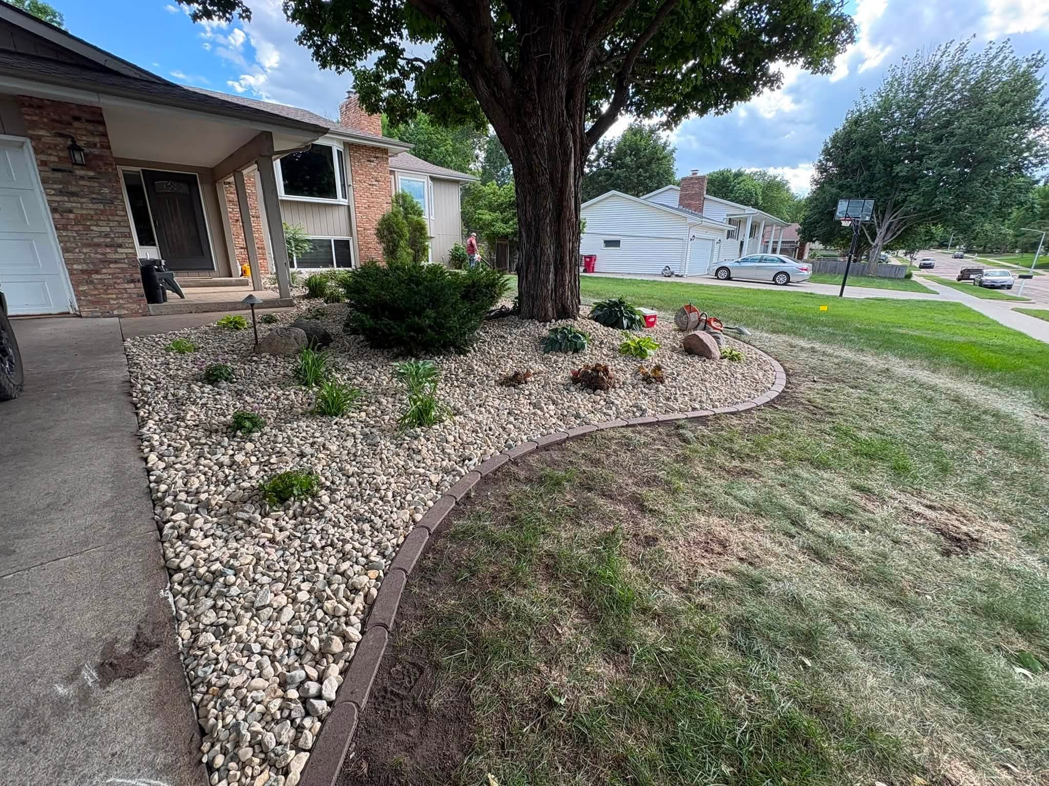 Curved rock edging and a green front lawn along the drive