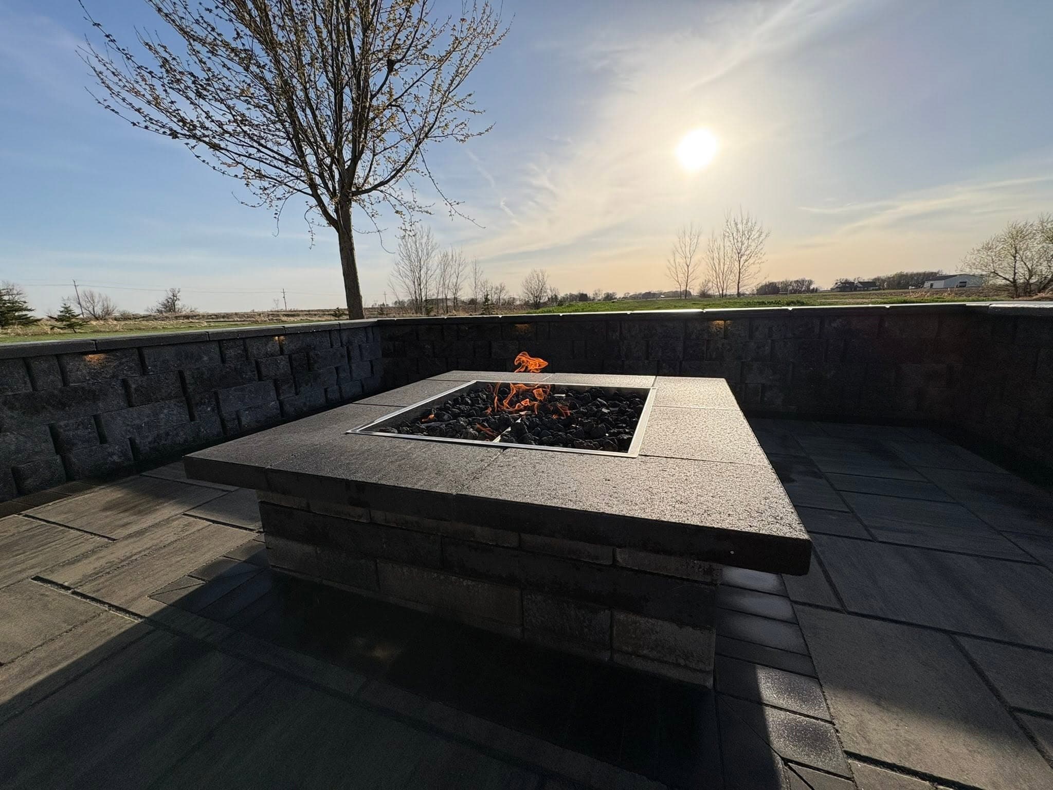 Fire table burning on a finished patio in the late-day sun